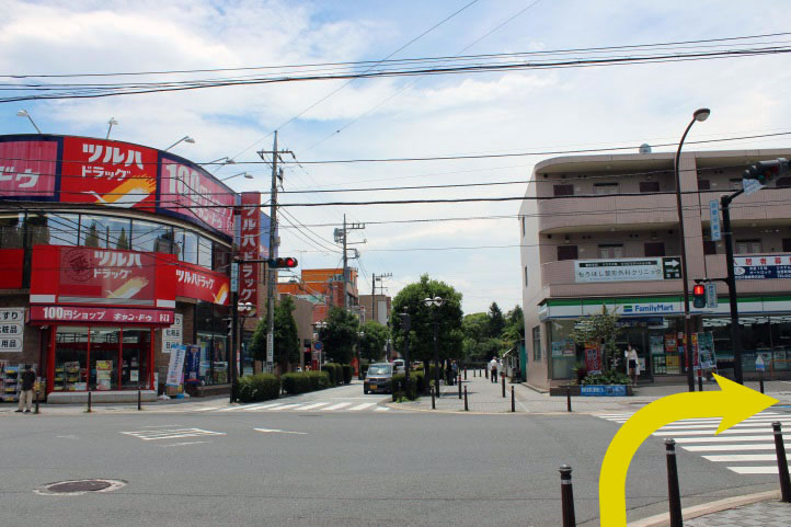 改札を背に、左手（南口）から地上へ降ります。駅前ロータリーの先に交差点があるので、横断歩道を渡って、ファミリーマートの前を右に曲がります。